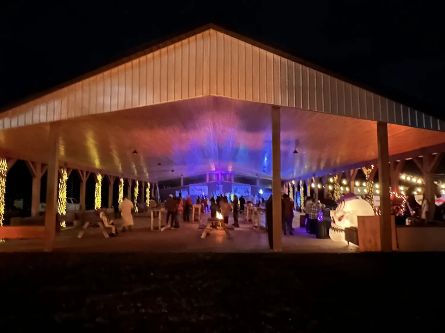 The covered pavilion lit up at night for a holiday party